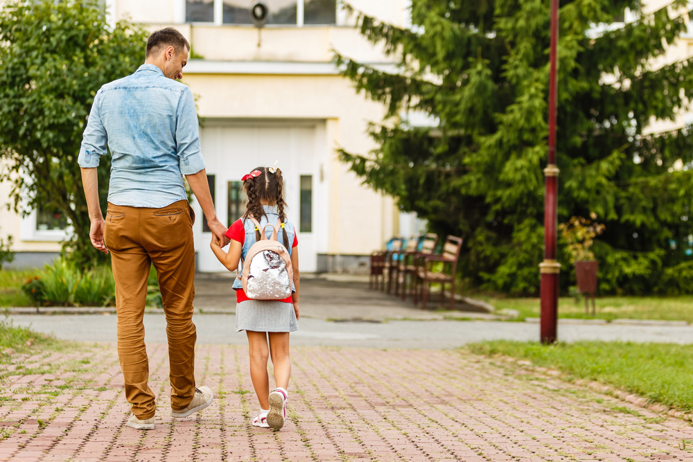 Father and step-daughter holding hands and walking towards a school - step-children's inheritance rights