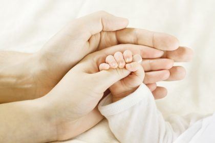 infant holding mothers hand