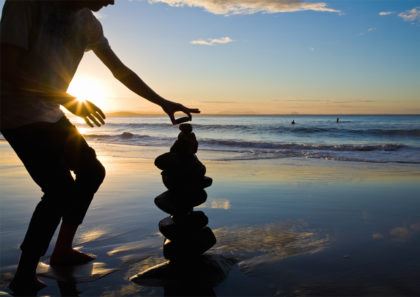 man stacking rocks on the beach