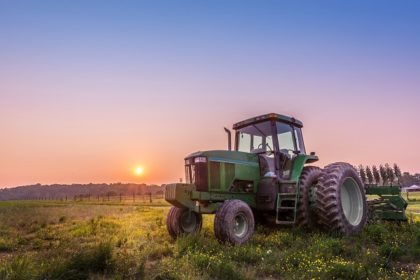 tractor in a field at sunset