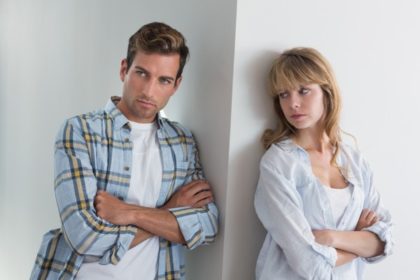 Unhappy man and woman leaning against a wall