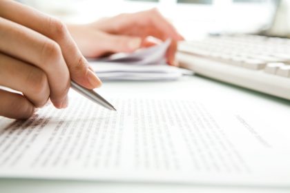 Person reading document with a pen.