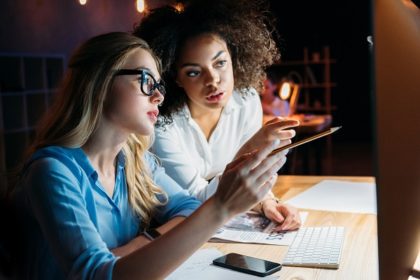 Two women discussing something that they see on a computer screen.