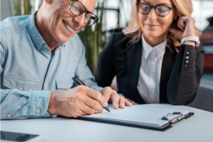 older couple signing a paper