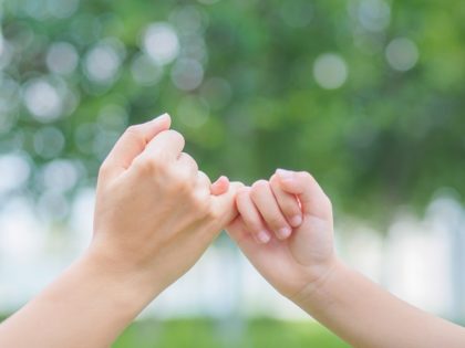 A parent and child making a pinky promise.