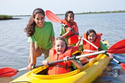 Four young women and a kayak in a lake.