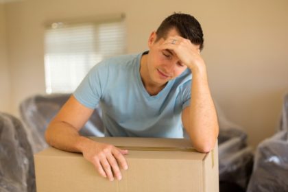 A man leans on a packing box with his head in his hand.