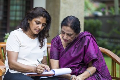 A woman and her mother sit on a bench outside, reviewing legal documents.
