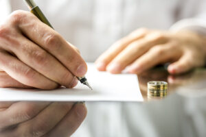 Closeup of a man signing divorce papers.