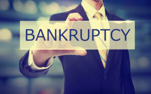 Business man holding Bankruptcy on blurred abstract background