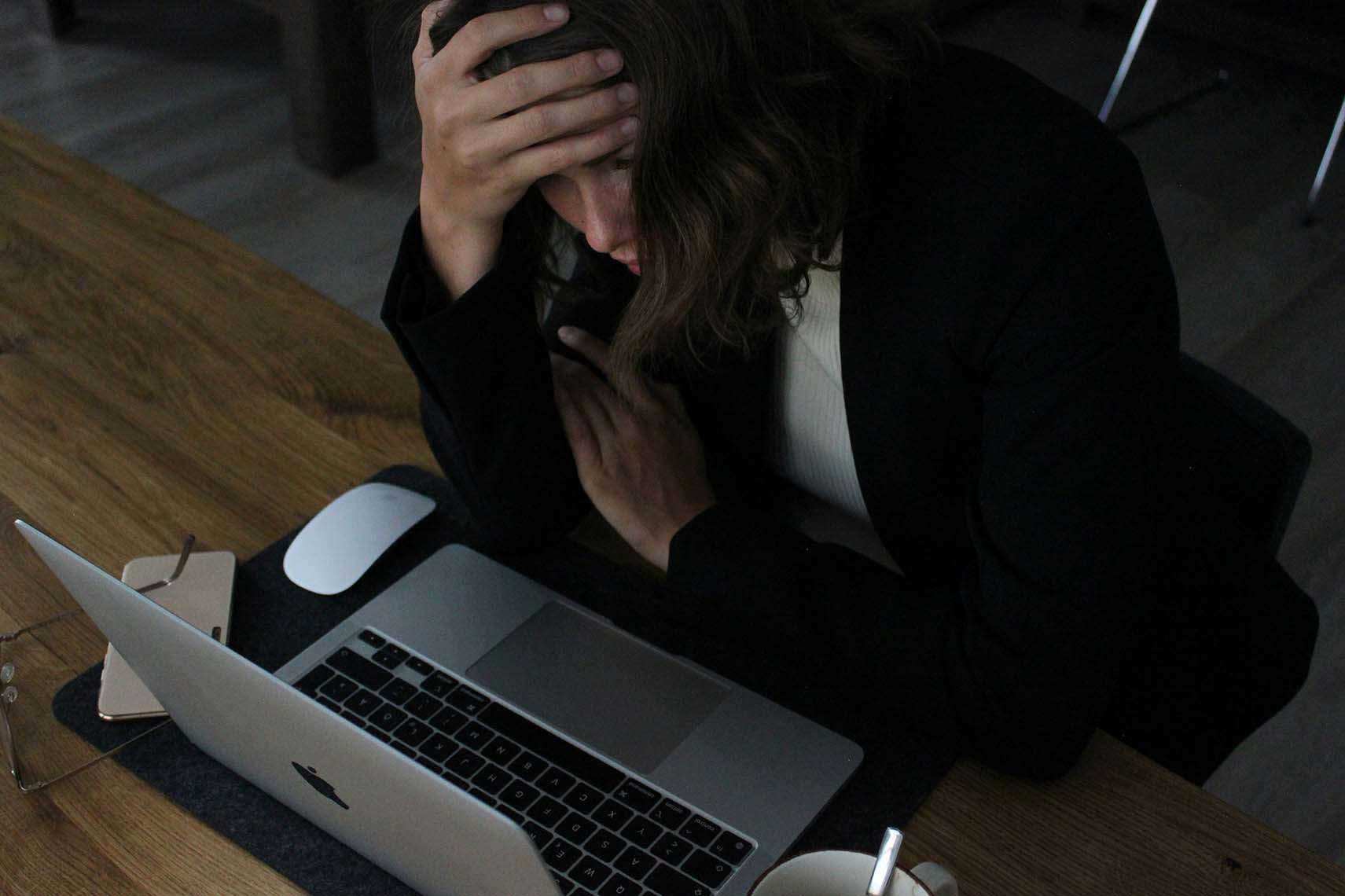 woman resting heaed in hand out of stress in front of her computer