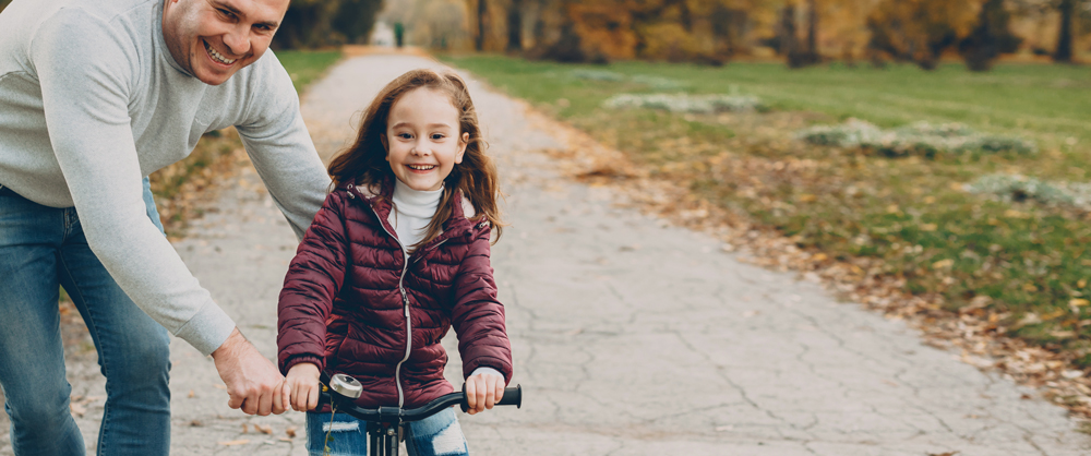 Dad helping daughter learn how to ride a bike - crafting an effective parenting plan