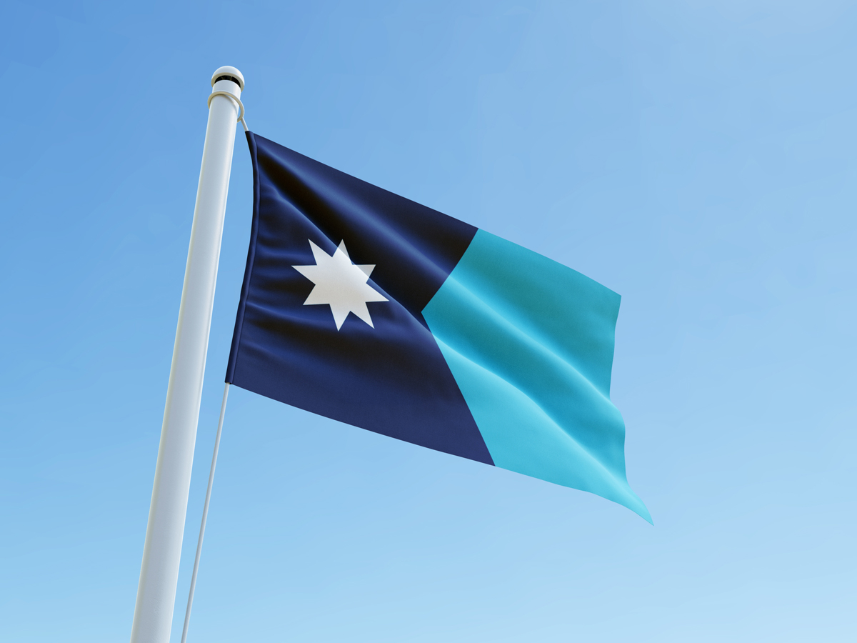 New Minnesota State flag blowing in the wind against a clear blue sky.