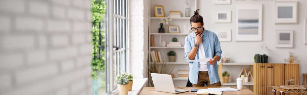 Man standing at desk looking at pepers