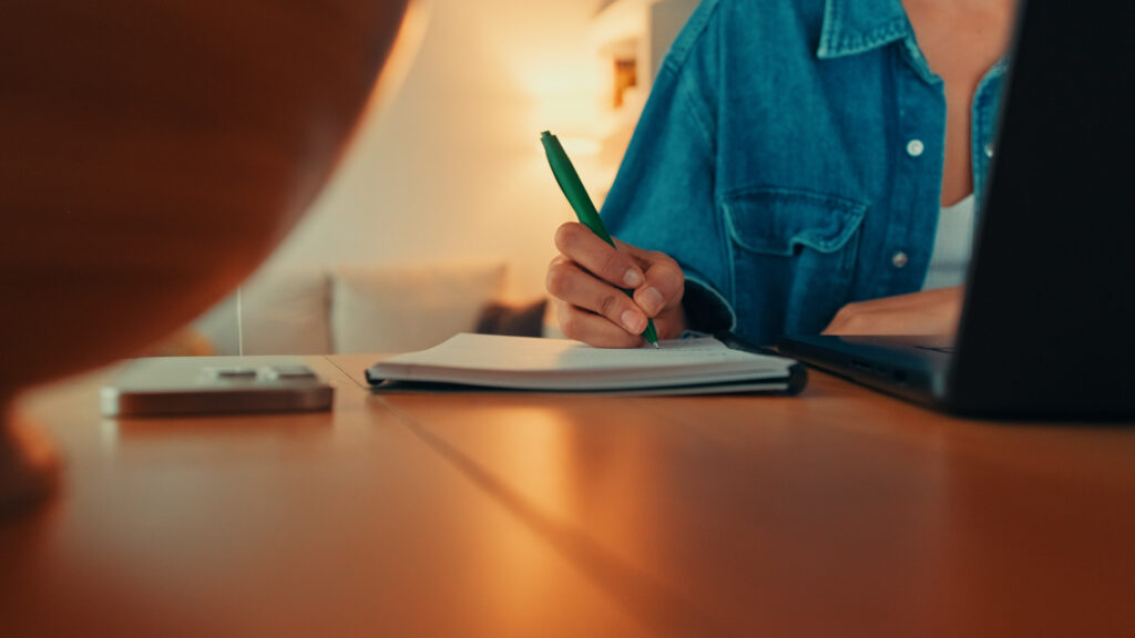 Close up of pen and paper pad on desk - woman taking notes