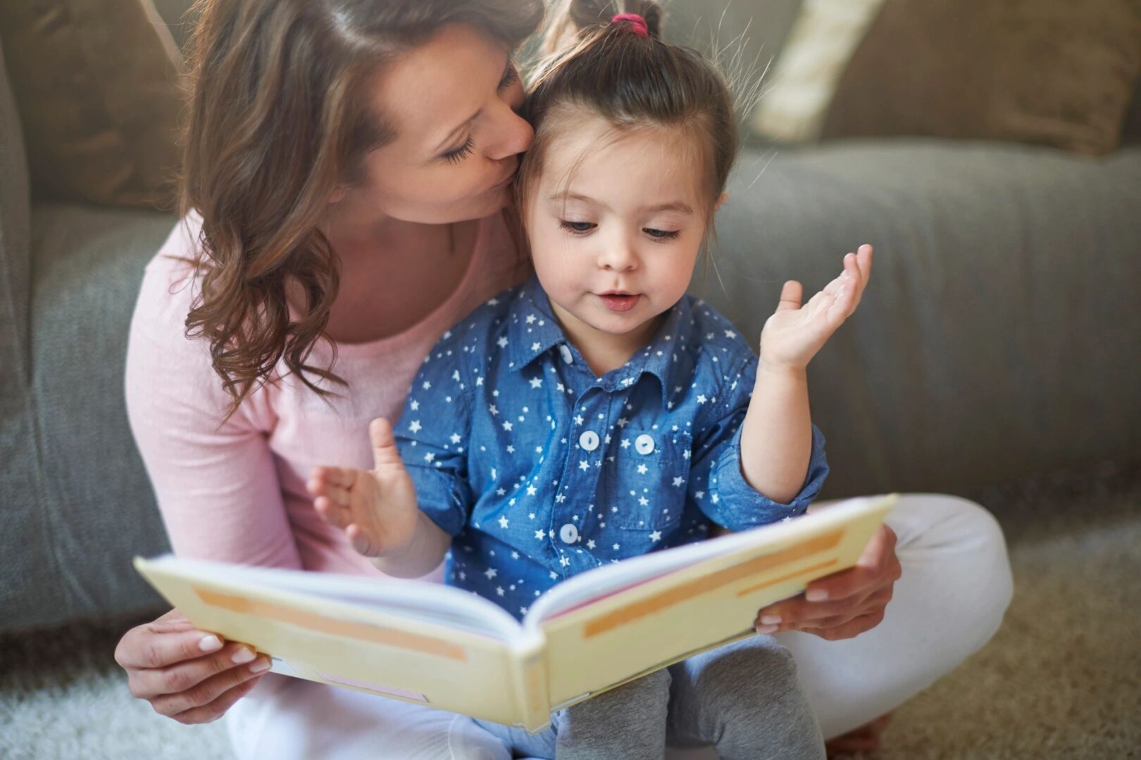 little girl sitting in mothers lap reading a book