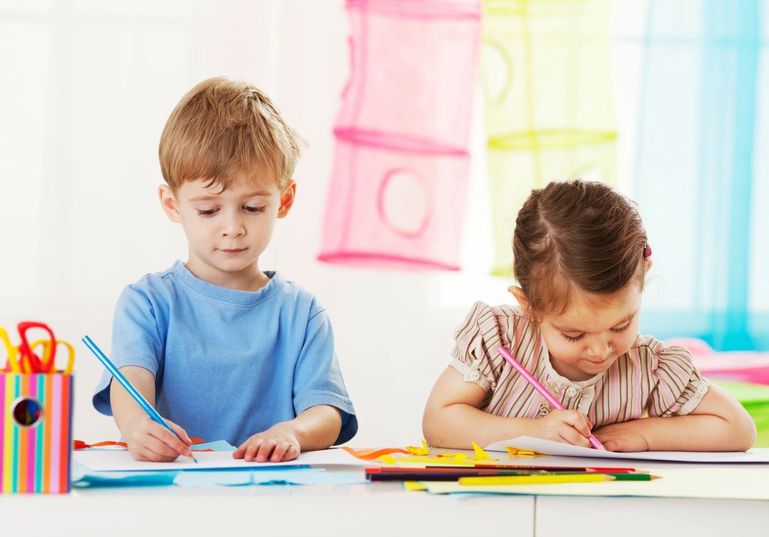 a boy and a girl sitting at a table coloring