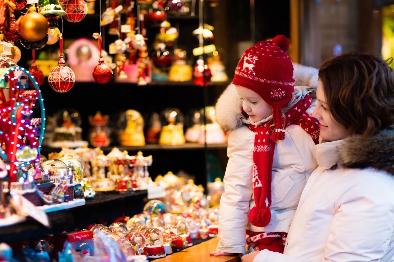 Mom holding daughter looking into a christmas store