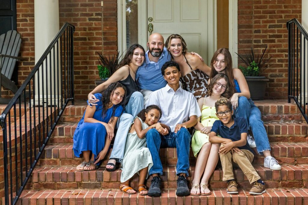 blended family posing for a family portrait on red brick steps in front of their home